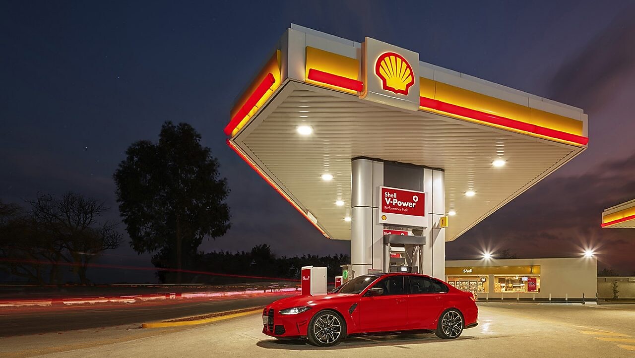 Coche rojo estacionado em estación de servicio de Shell a la noche