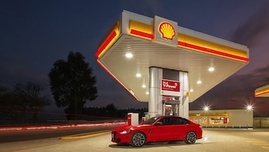 Coche rojo estacionado em estación de servicio de Shell a la noche