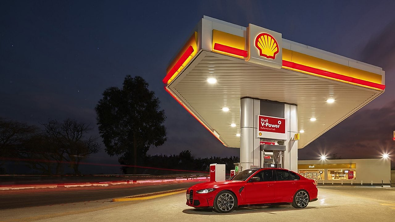 Coche rojo estacionado em estación de servicio de Shell a la noche