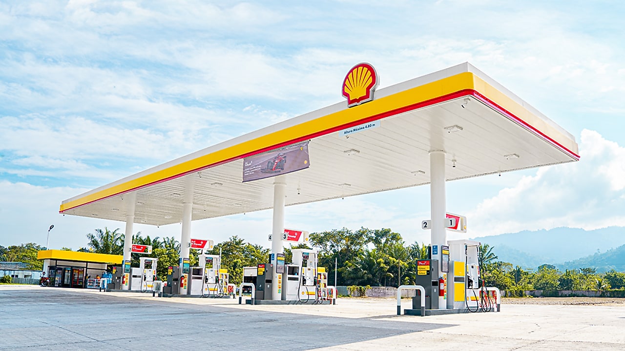Estación de servicio Shell en Honduras con múltiples surtidores de combustible, ubicada en entorno natural con montañas al fondo.