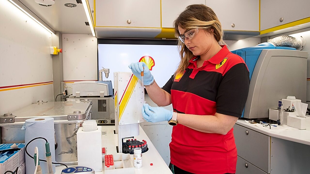 Una mujer blanca con cabello rubio trabaja en el laboratorio de la Alianza de Shell con Ferrari