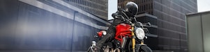 Motociclista con ropa negra y casco sobre motocicleta roja