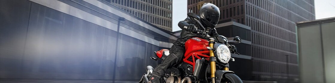 Motociclista con ropa negra y casco sobre motocicleta roja