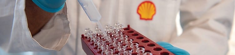 Mano con guante de laboratorio trabajando en viales con líquido transparente