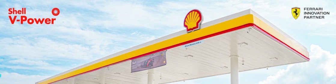Coche rojo estacionado em estación de servicio de Shell a la noche