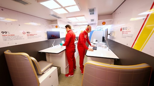 Dos hombres de uniforme rojo de la Alianza Shell y Ferrari trabajan en sus computadoras